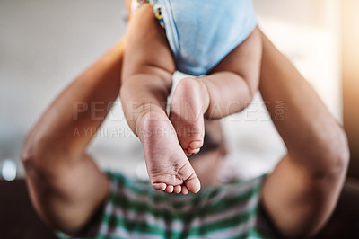 Buy stock photo Closeup, legs and baby with father, love and playing with joy, happiness and bonding in the lounge. Zoom, dad and infant in the air, home and games with child development, fun and family on a couch