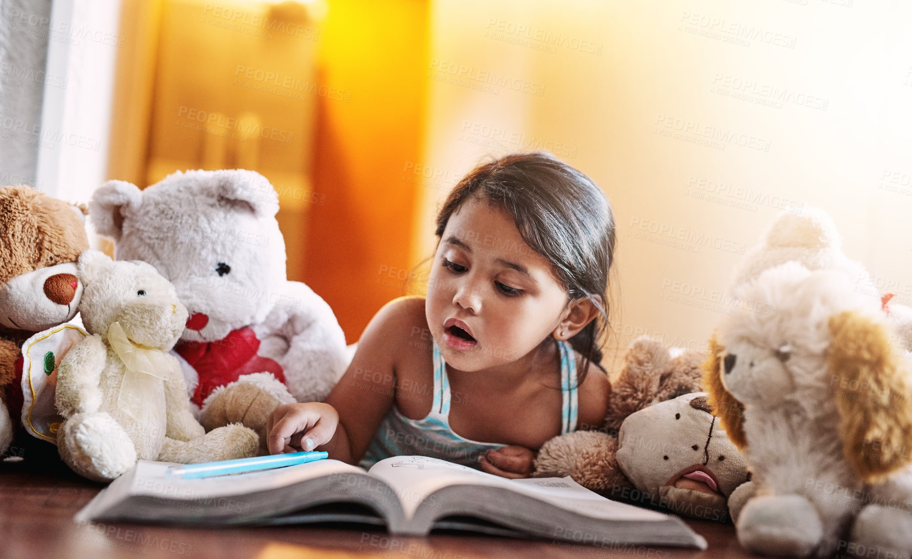 Buy stock photo Shot of a focused little girl writing inside of a book while lying on the floor at home during the day