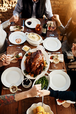 Buy stock photo Food, table and people praying and holding hands while eating together for holiday celebration. Above group of family or friends pray for thanksgiving lunch, chicken or turkey and wine drinks