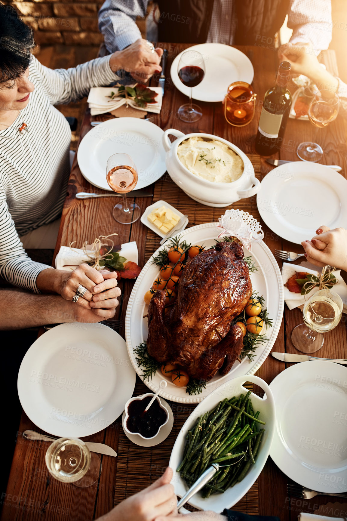 Buy stock photo Food, celebration and people praying and holding hands at a table together for thanksgiving holiday. Above group of family or friends pray for gratitude for healthy lunch, turkey and wine in house