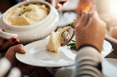 Buy stock photo Cropped shot of an unrecognizable woman dishing mash during a feast at a dining table on Thanksgiving