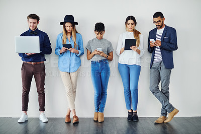 Buy stock photo Shot of a group of creative employees using wireless technology while standing in line