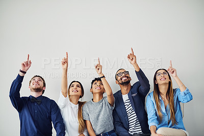 Buy stock photo Shot of a group of young people pointing towards something above them inside