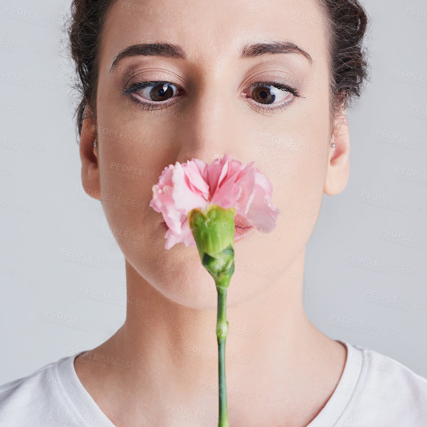 Buy stock photo Studio shot of a beautiful young woman smelling a pink flower against a grey background