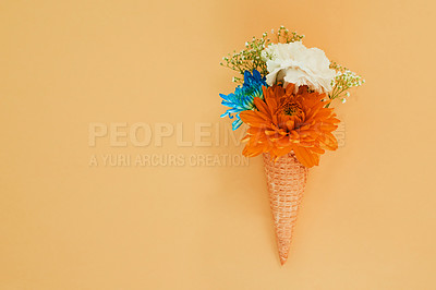 Buy stock photo Shot of a cone stuffed with flowers against a colorful background