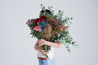 Buy stock photo Nature, gift and woman with flowers, creative aesthetics and beauty against a grey background. Female person, model and girl with a floral present, bouquet and covering face with natural products