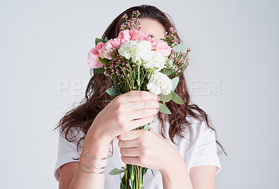 Buy stock photo Studio shot of an unrecognizable woman covering her face with flowers against a grey background
