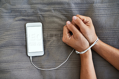 Buy stock photo High angle shot of an unrecognizable person's hands bound by a cellphone cable