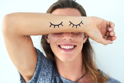 Buy stock photo Studio shot of a young man raising his arm with eyelash illustrations on in front of his eyes