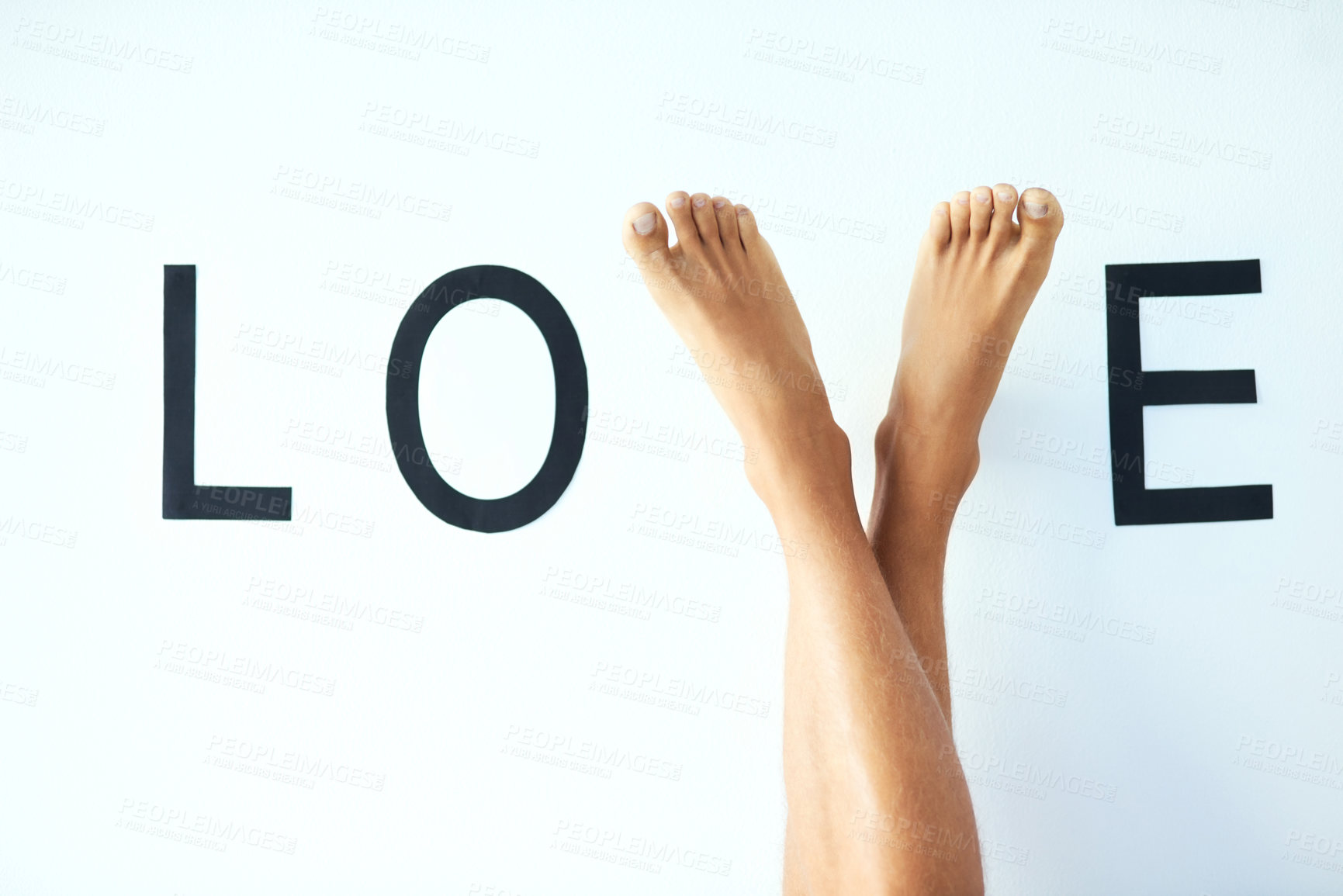 Buy stock photo Studio shot of an unrecognizable man's crossed legs with his feet forming the letter 