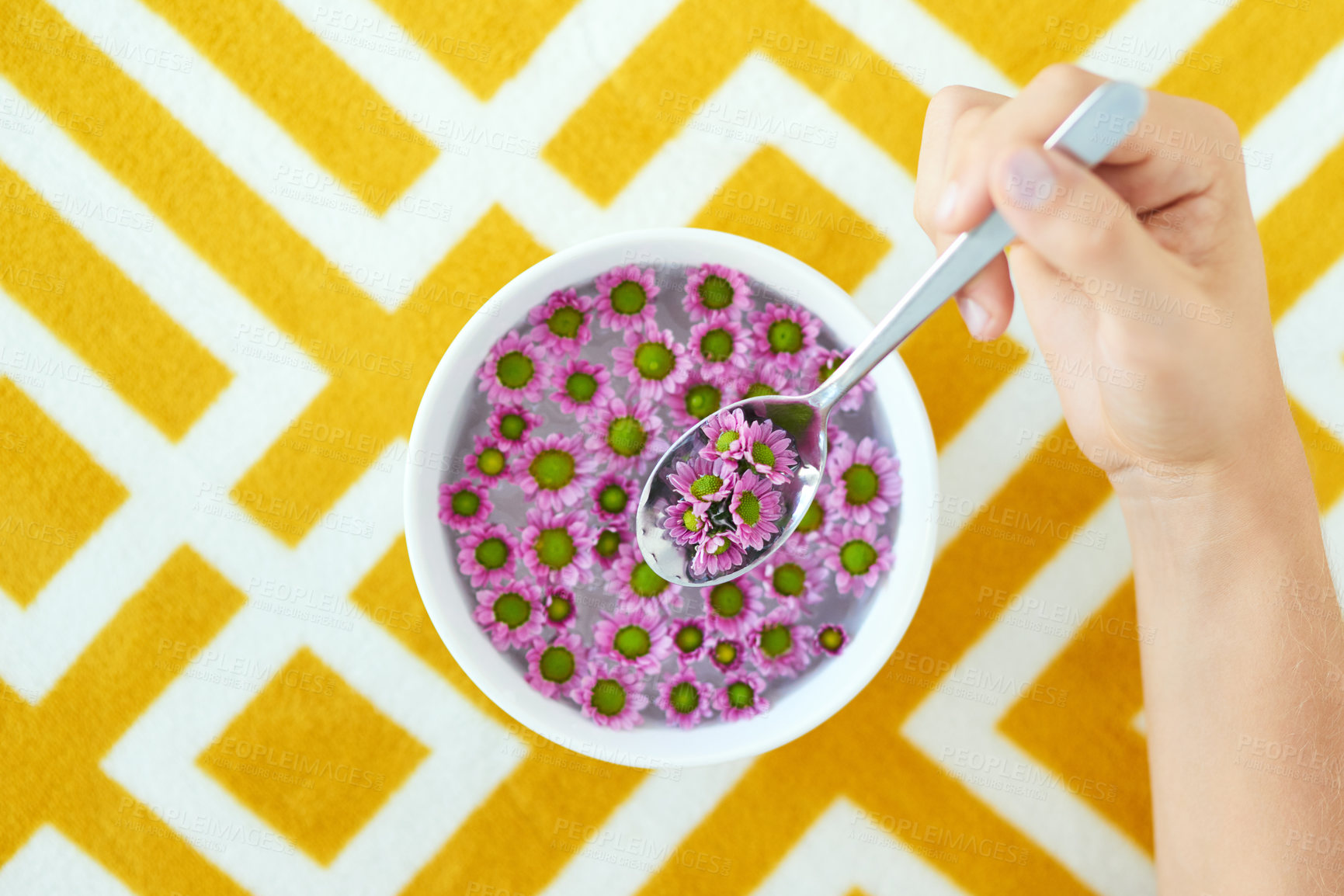 Buy stock photo Bowl, spoon and hands with flowers for eating cereal, porridge or breakfast meal by abstract table. Food, plants and high angle of person with floral for nourishment, nutrition or vitamins of nature.