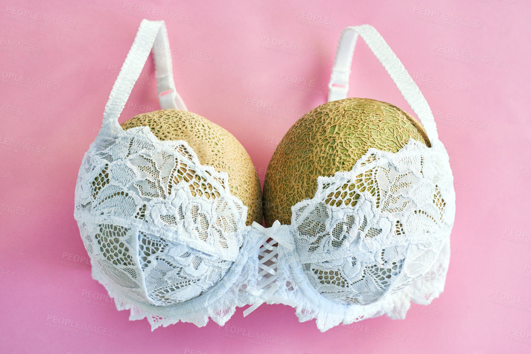 Buy stock photo Studio shot of melons in a bra against a pink background