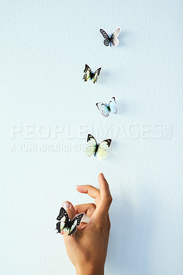 Buy stock photo Studio shot of an unrecognizable person releasing butterflies into the air against a grey background