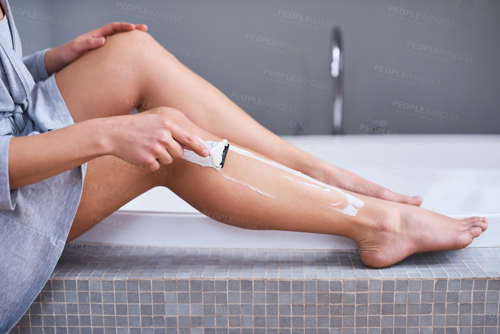 Buy stock photo Closeup shot of an unrecognizable woman shaving her legs in the bathroom at home