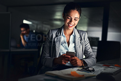 Buy stock photo Woman reading text late on phone, smiling at a message and looking at social media posts online while working in a dark office at night. Happy corporate worker checking emails and doing overtime