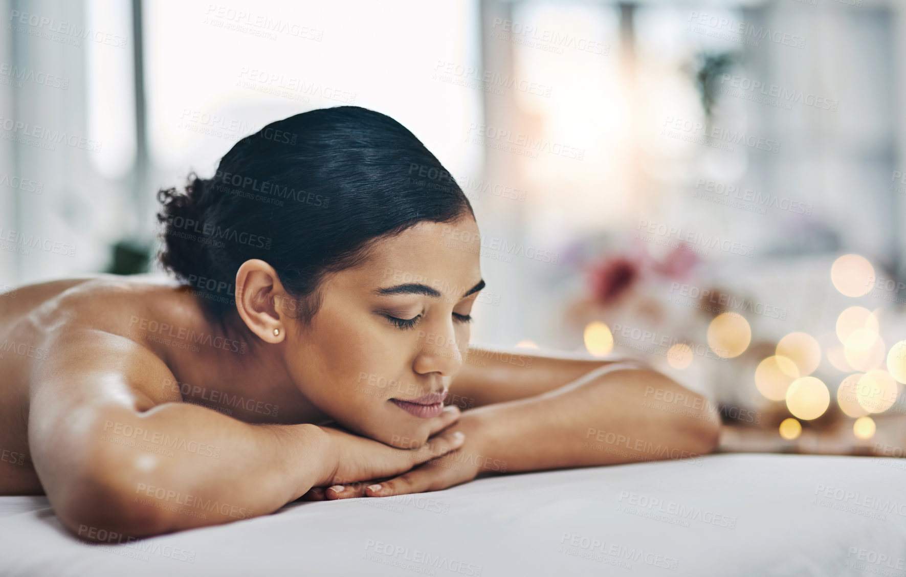 Buy stock photo Shot of a relaxed an cheerful young woman getting a massage indoors at a spa