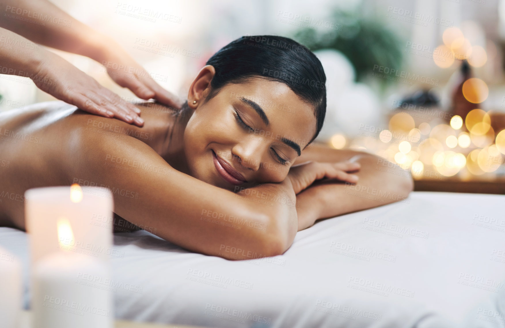 Buy stock photo Shot of a relaxed an cheerful young woman getting a massage indoors at a spa