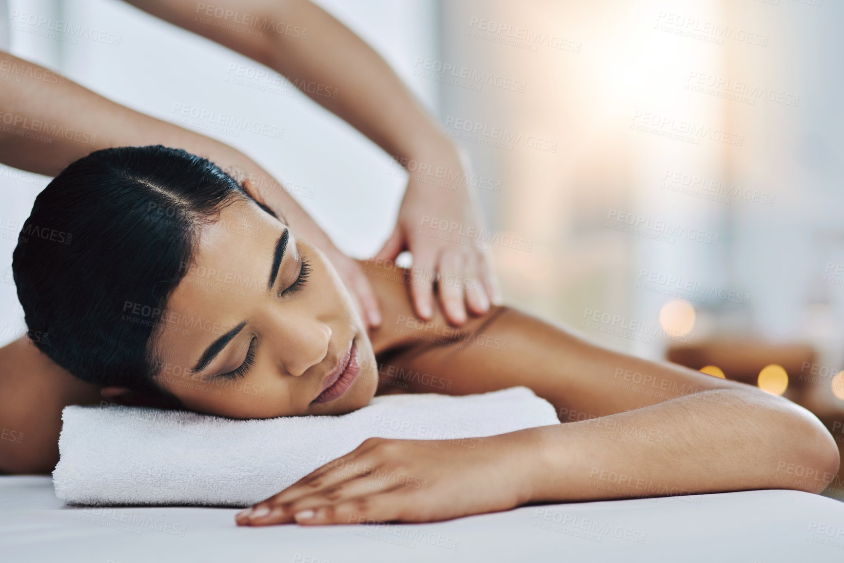 Buy stock photo Shot of a relaxed an cheerful young woman getting a massage indoors at a spa