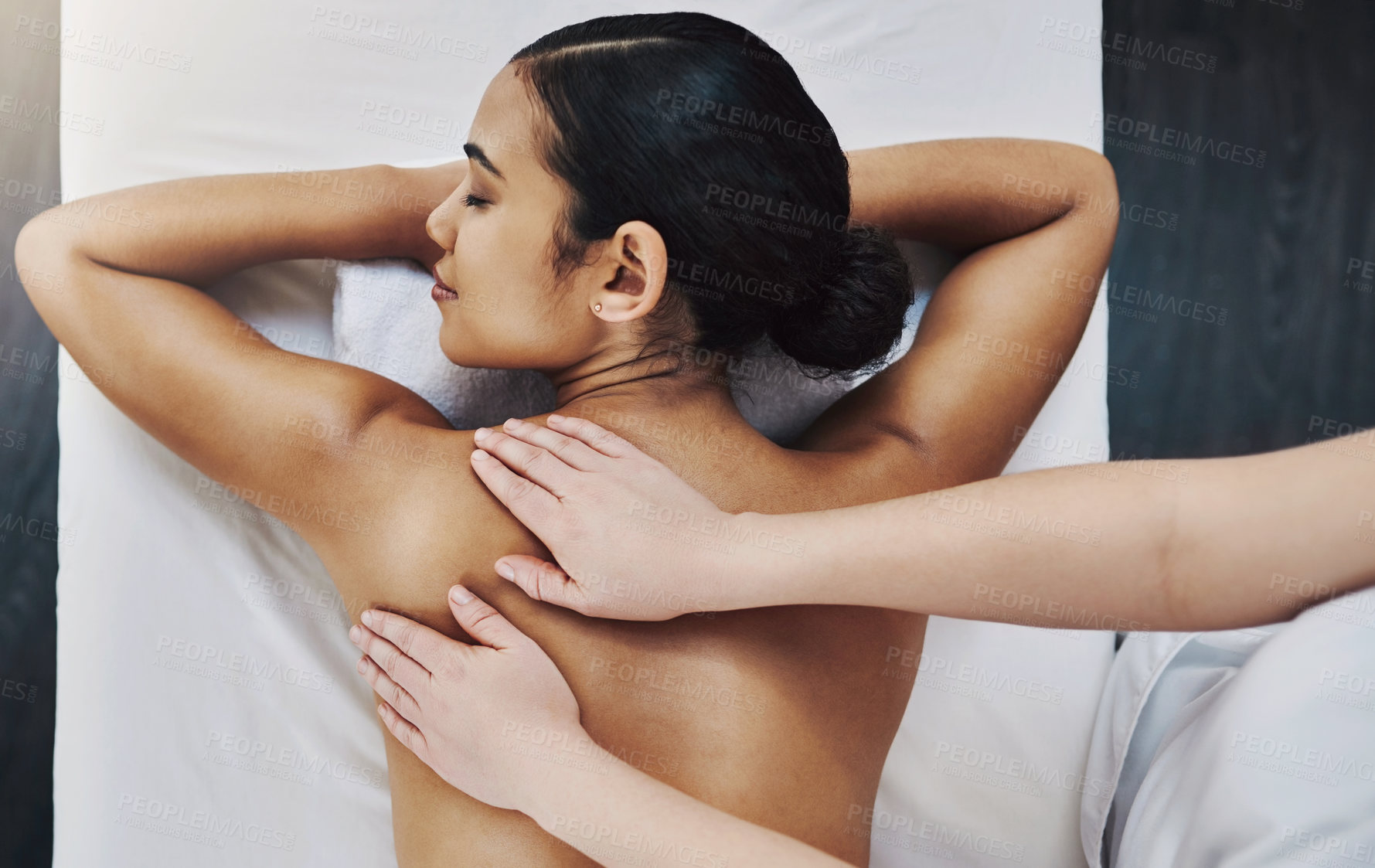 Buy stock photo Shot of a relaxed an cheerful young woman getting a massage indoors at a spa