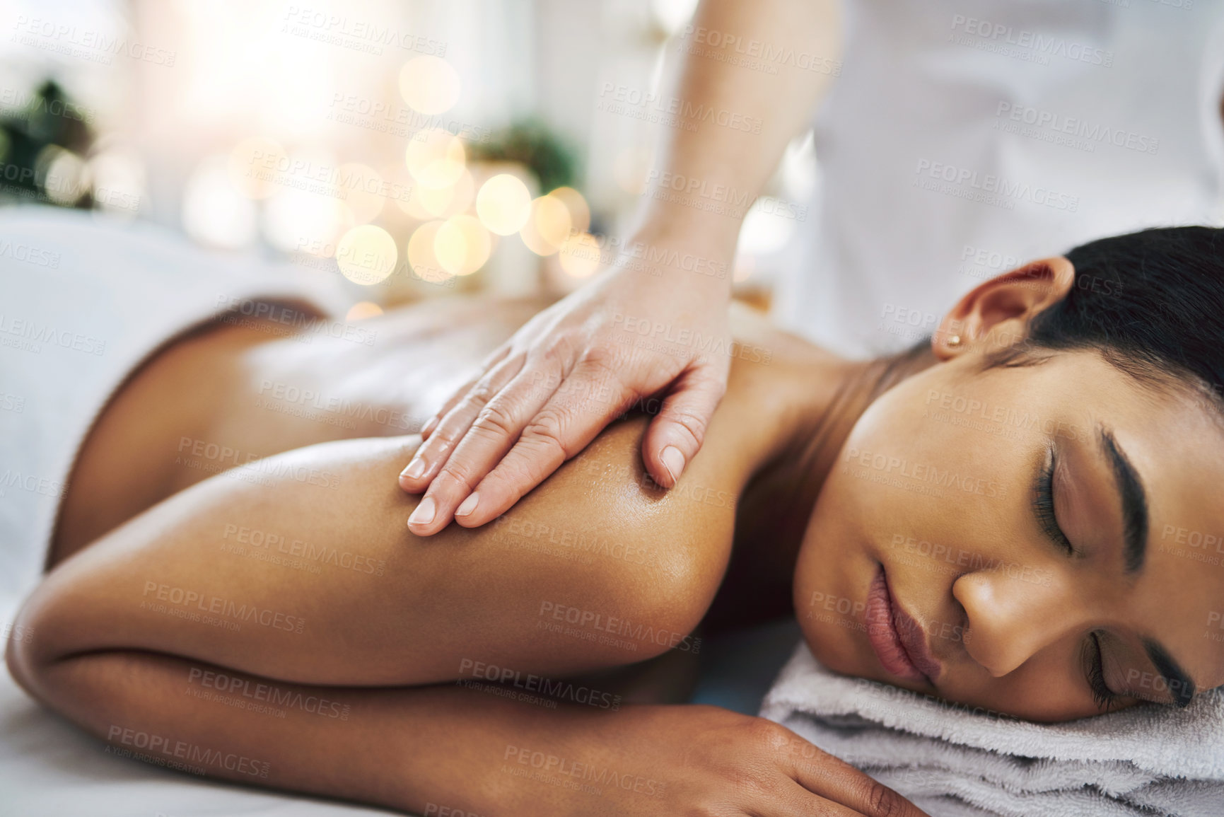 Buy stock photo Shot of a relaxed an cheerful young woman getting a massage indoors at a spa