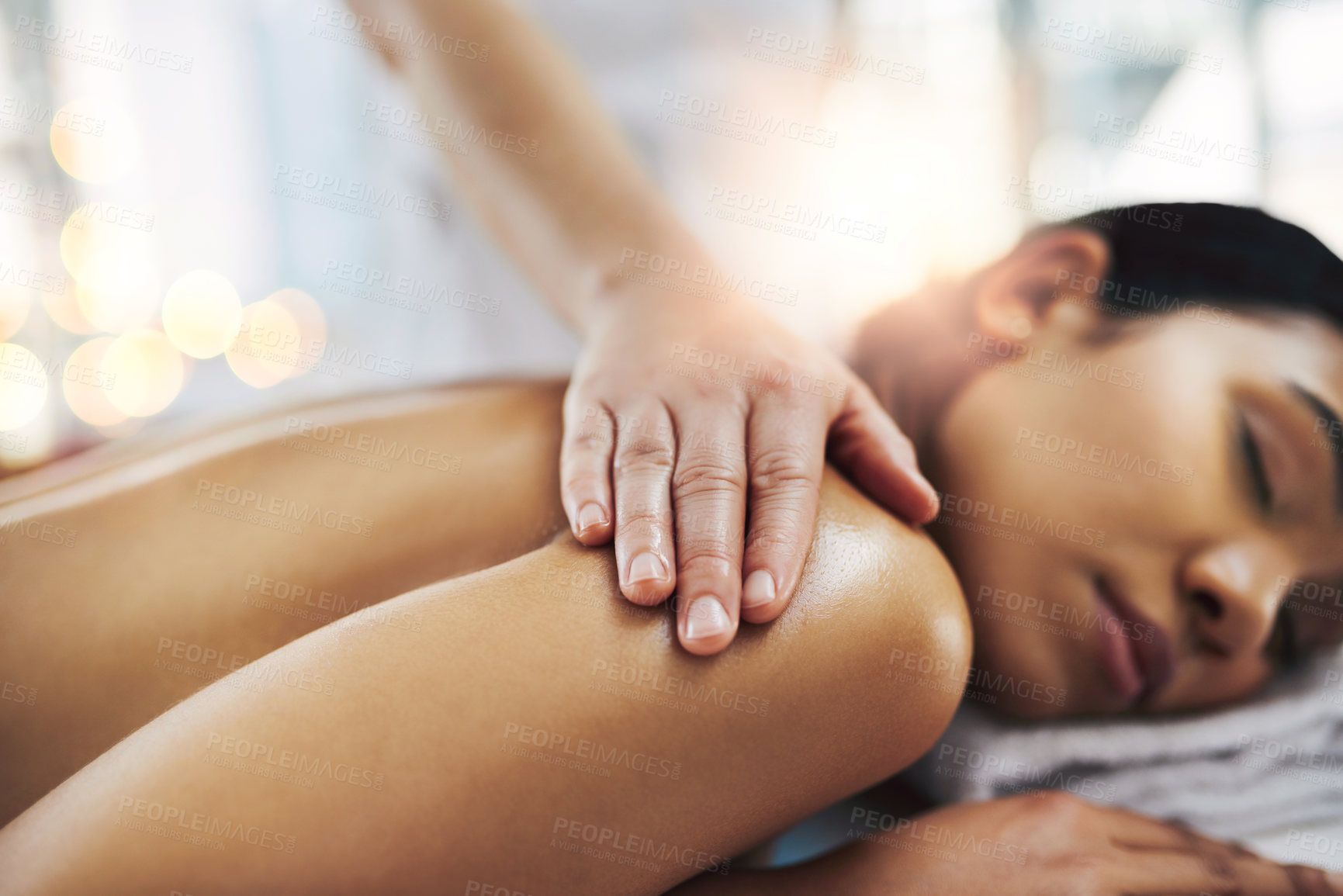 Buy stock photo Shot of a relaxed an cheerful young woman getting a massage indoors at a spa