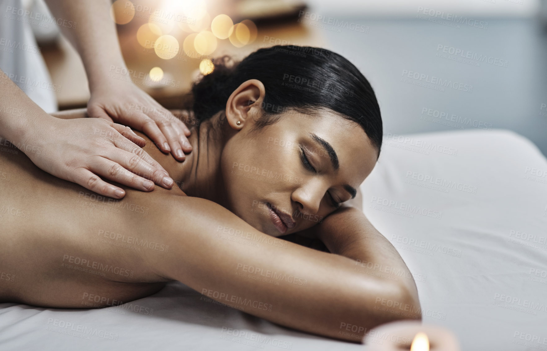 Buy stock photo Shot of a relaxed an cheerful young woman getting a massage indoors at a spa