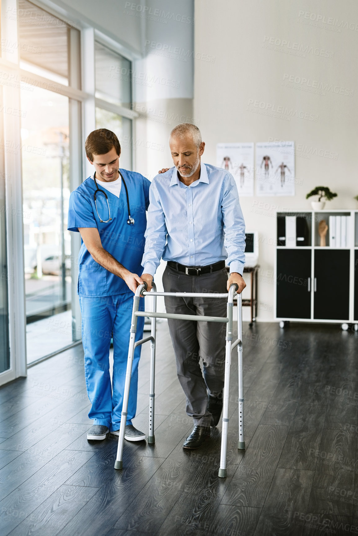 Buy stock photo Shot of a male nurse assisting a senior patient with a walker