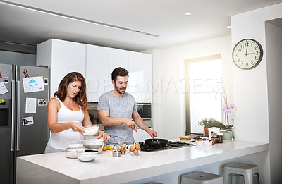 Buy stock photo Shot of a happy young couple preparing breakfast in the morning