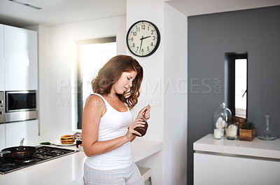Buy stock photo Shot of young woman standing in the kitchen indulging on a sweet delight