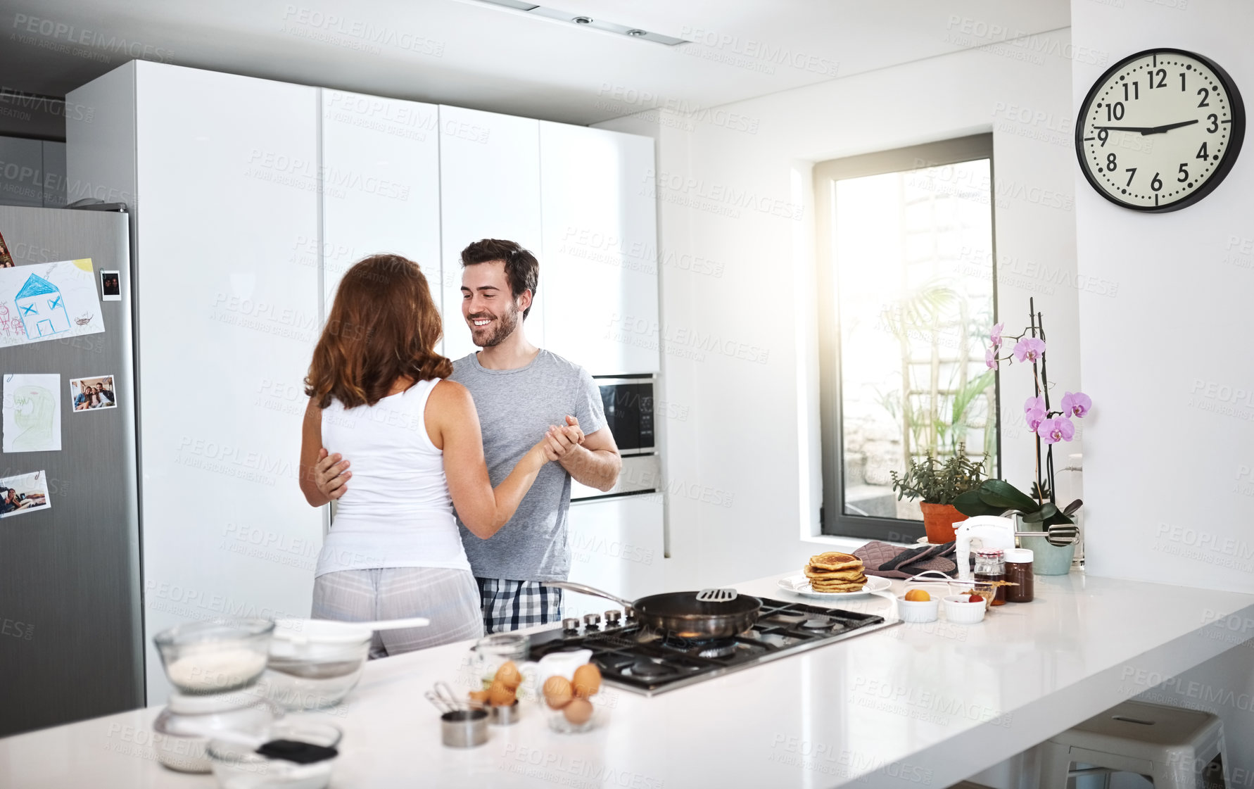 Buy stock photo Shot of young couple dancing in the kitchen while preparing breakfast