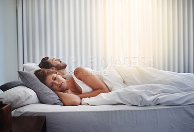 Buy stock photo Shot of a woman looking upset while her husband sleeps beside her at home