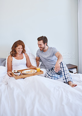 Buy stock photo Shot of a couple enjoying breakfast in bed together at home