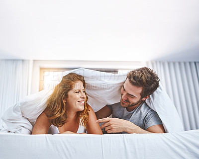 Buy stock photo Shot of a couple relaxing together underneath a blanket at home