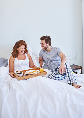 Buy stock photo Shot of a couple enjoying breakfast in bed together at home