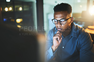 Buy stock photo Cropped shot of a handsome young businessman looking thoughtful while working late at night in a modern office