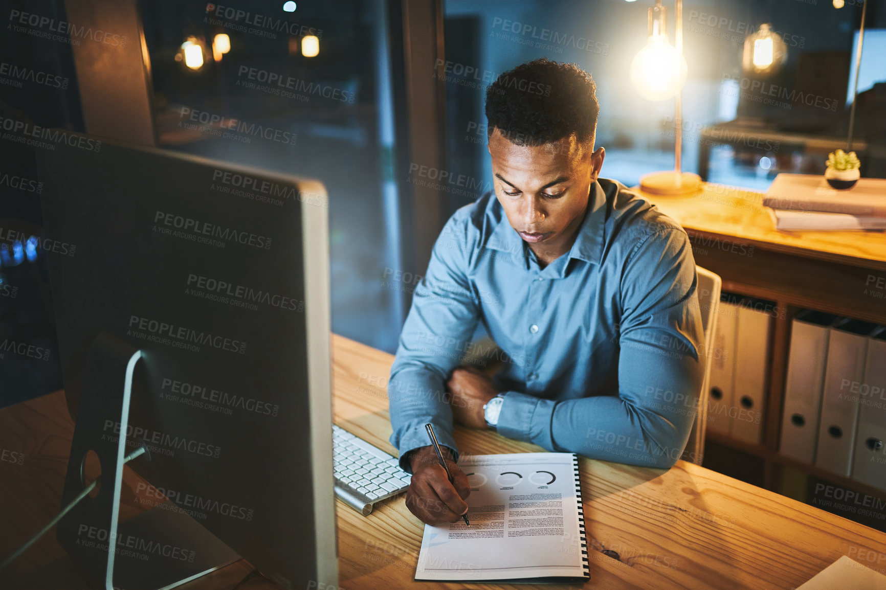 Buy stock photo Dark, office and black man at computer with notes, business plan and data analysis at desk at tech startup. Night, thinking and businessman with ideas, paperwork and research report at digital agency