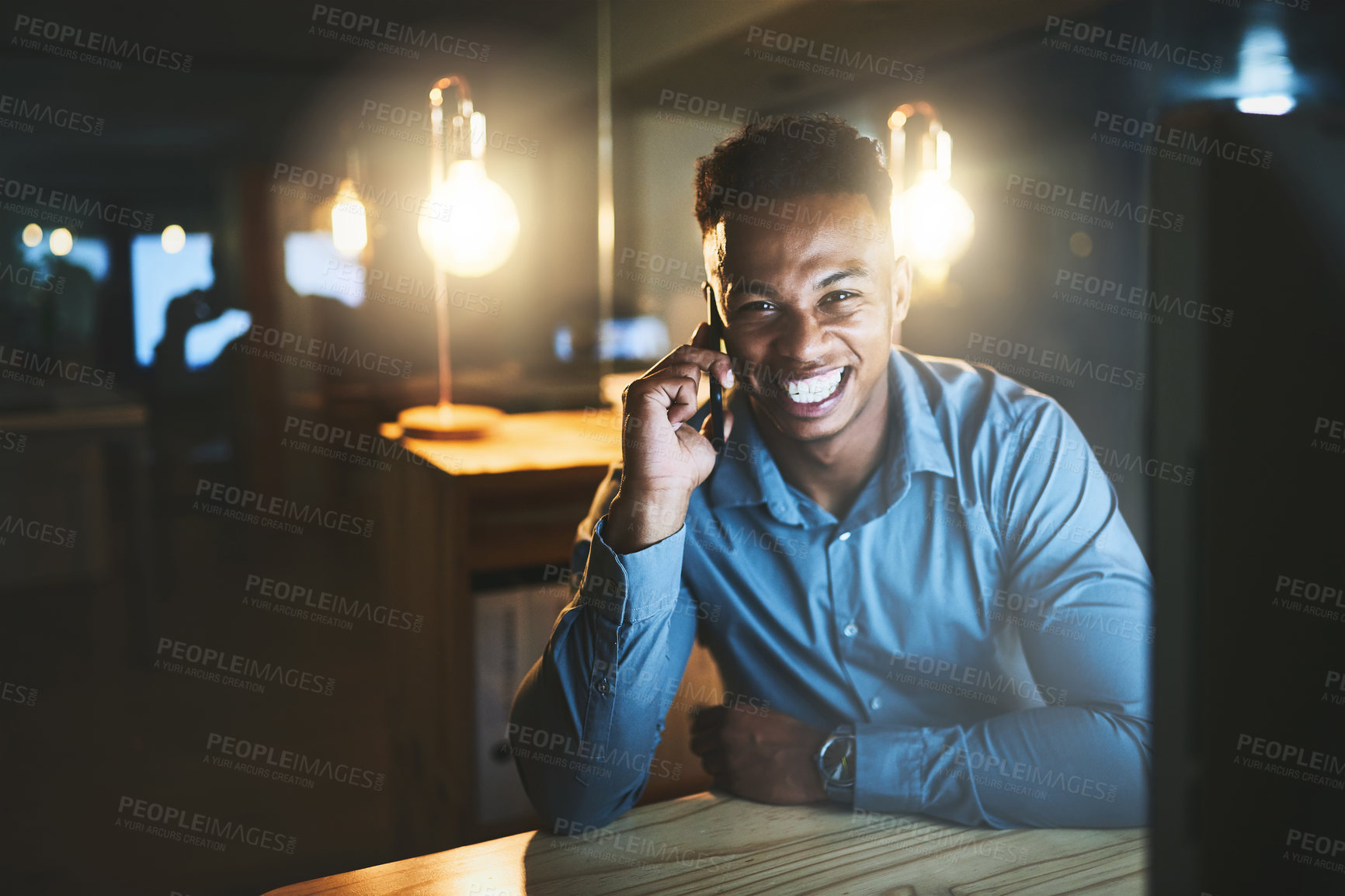Buy stock photo Cropped portrait of a handsome young businessman making a phonecall while working late at night in a modern office