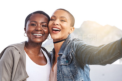 Buy stock photo Portrait of two young women smiling and posing while taking a selfie in the city