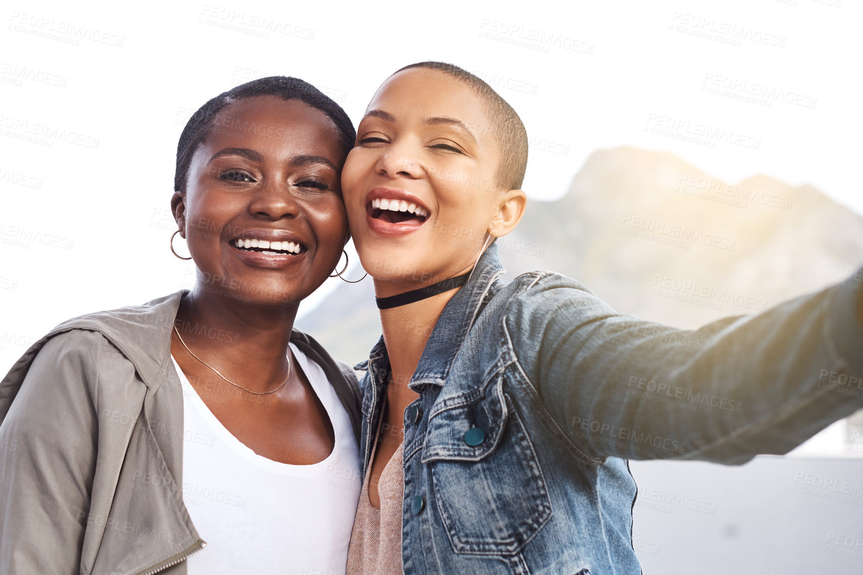 Buy stock photo Portrait of two young women smiling and posing while taking a selfie in the city