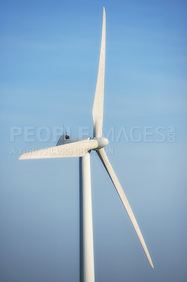 Buy stock photo Closeup of a modern windmill against a blue sky background outside. Wind turbine generating electricity through spinning a generator on propeller blades. Concept for renewable and sustainable energy