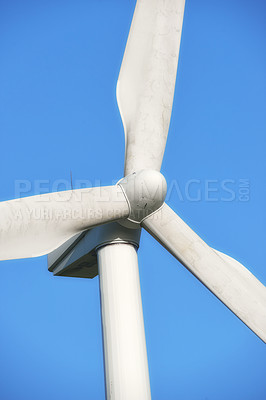 Buy stock photo Renewable and sustainable energy generated by a modern wind turbine against a blue sky background outside. Wind energy or power generating clean electricity or mechanical power using rotating blades