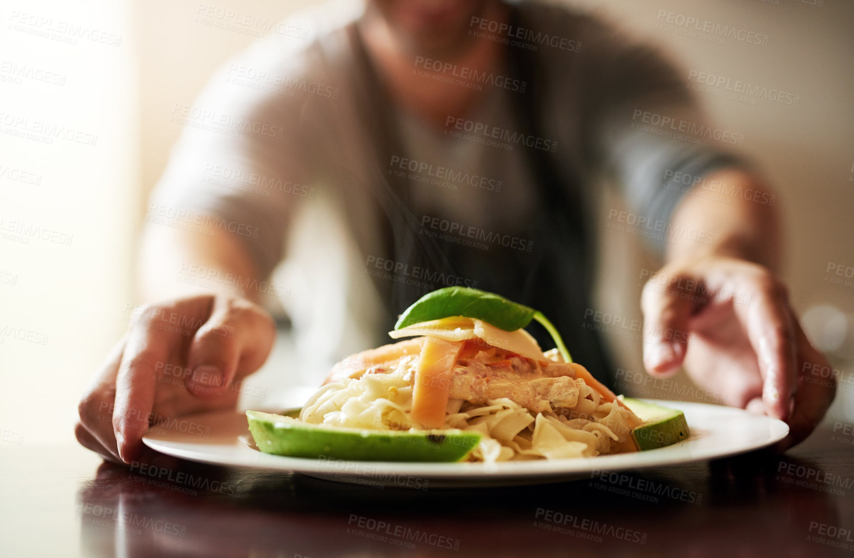 Buy stock photo Cropped shot of an unrecognizable young man serving food in the kitchen at home