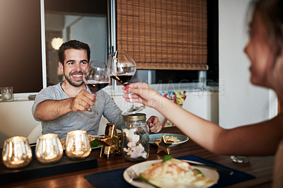Buy stock photo Cropped shot of an affectionate young couple toasting while enjoying a meal at home