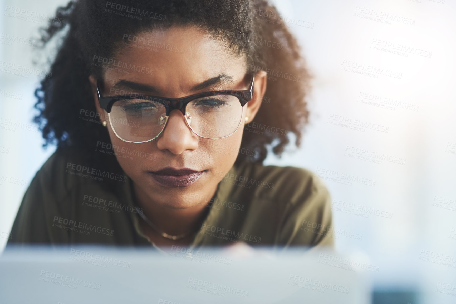 Buy stock photo Shot of a young businesswoman busy working on her laptop in a modern office