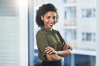 Buy stock photo Portrait of a confident young businesswoman standing in her office with her arms folded