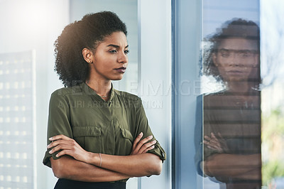 Buy stock photo Shot of a young businesswoman looking out of a window in her office