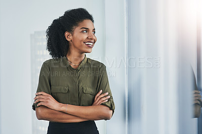 Buy stock photo Shot of a confident young businesswoman looking out of a window in her office