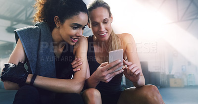 Buy stock photo Fitness, phone and girl friends watching a video in a gym with women and smile from training. Social media app, mobile and female person in wellness, exercise and workout class taking a break