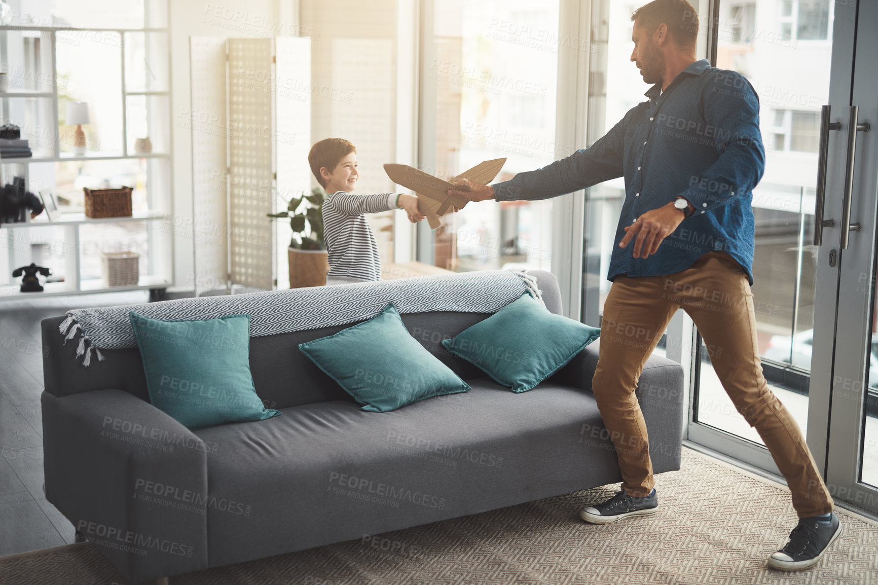 Buy stock photo Shot of a cheerful little boy and his father playing around together while being in the living room