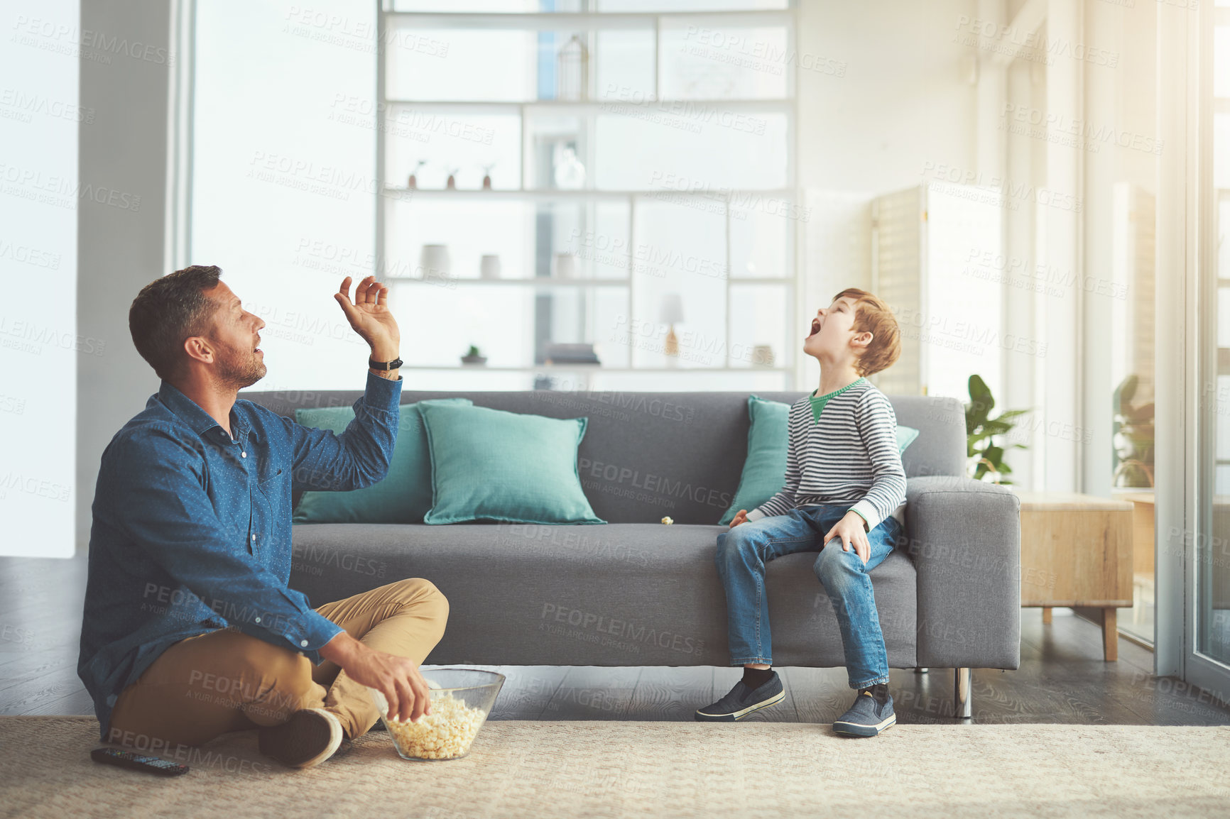 Buy stock photo Shot of a carefree little boy and his father playing around in the living room at home during the day